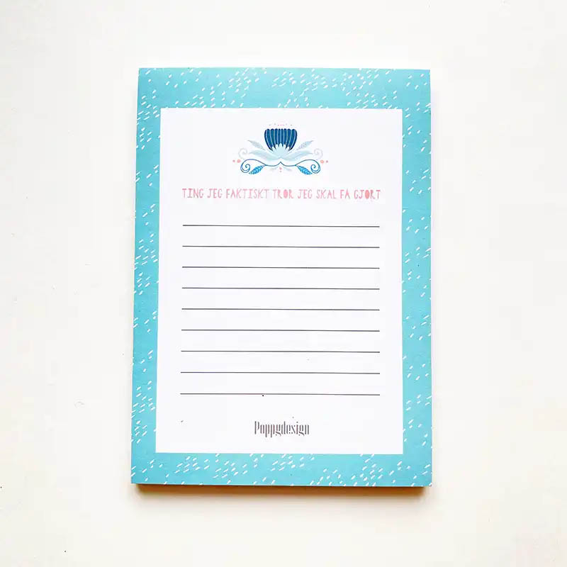 Bilde av en notatblokk med blå kant og blomstermotiv.